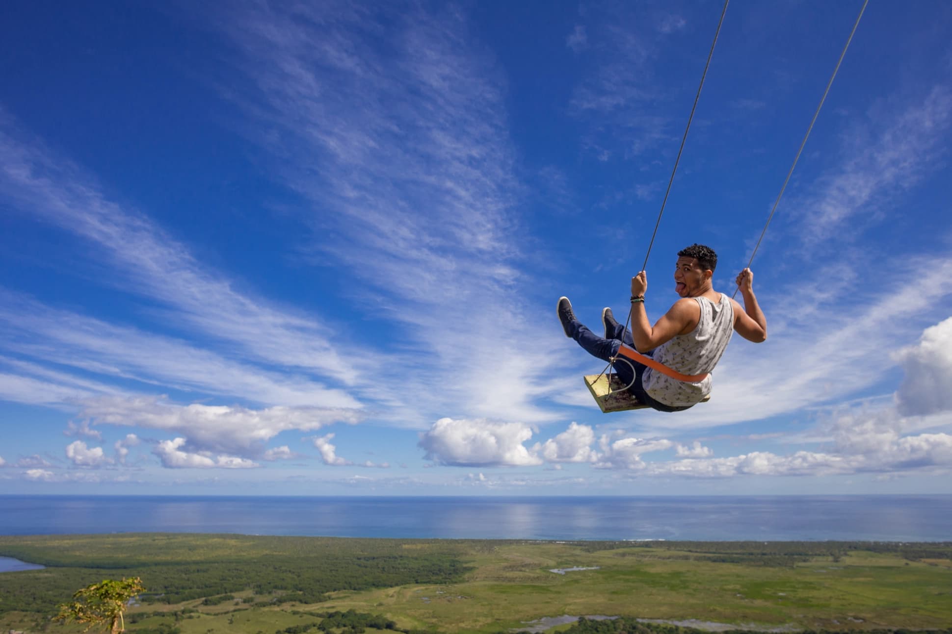 Man enjoying the giant swing at Montaña Redonda with panoramic ocean views in the Dominican Republic.